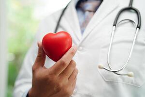 médico de mulher asiática segurando coração vermelho para saúde no hospital. foto