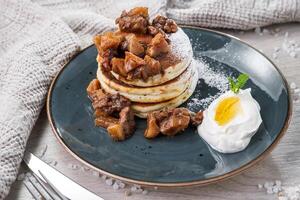 panquecas com caramelizado maçãs e azedo creme em uma prato foto