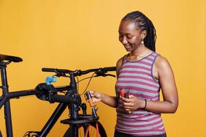 saudável Preto mulher preparando profissional Ferramentas para bicicleta reparar e manutenção. africano americano fêmea fixação uma bicicleta, inspecionando, ajustando, e protegendo Está componentes com especialista precisão. foto