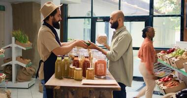 comprador apresenta temperos e produtos dentro vidro frascos para vegano cliente enquanto ele é compras para mantimentos. meio Oriental homem quer para Comprar orgânico natural fresco frutas e legumes. foto