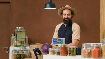 local agricultor fornecedor ponderação produzir às dinheiro registro contador, usando eletrônico escala para determinar peso e preços. jovem homem lojista encorajando saudável comendo e sustentável estilo de vida. foto