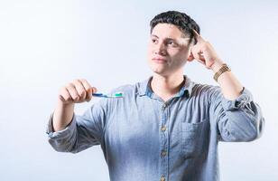 pensativo homem segurando escova de dente isolado. pensativo pessoa segurando escova de dente e olhando acima isolado foto