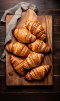 ai gerado croissants em uma corte borda em uma de madeira fundo, topo Visão foto