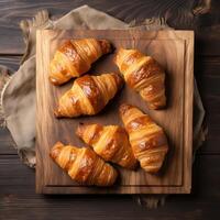 ai gerado recentemente cozido croissants em uma de madeira quadro, topo Visão foto