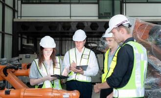 grupo do engenheiros e técnicos trabalhando juntos dentro uma robótico braço fábrica. inspecionando robô braço antes entregando para clientes foto