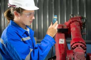 engenheiros e técnicos trabalhando juntos dentro uma robótico braço fábrica, Verifica a poder transmissão linhas do a robótico braço. foto