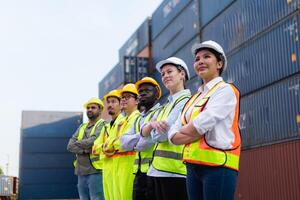 grupo do trabalhador vestindo segurança capacete e reflexivo colete em pé dentro frente do containers. foto