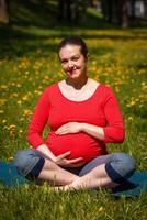 grávida mulher fazendo asana sukhasana ao ar livre foto