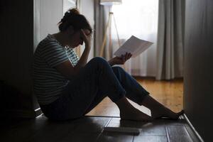 silhueta do uma triste mulher sentado em a chão do dela apartamento foto