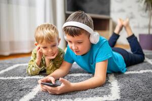 dois crianças assistindo inteligente telefone, feliz crianças usando smartphones juntos foto