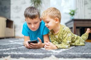 dois crianças assistindo inteligente telefone, feliz crianças usando smartphones juntos foto