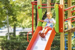 uma Garoto tendo Diversão enquanto jogando em a Parque infantil dentro a dia dentro verão foto