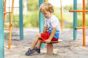 uma Garoto tendo Diversão enquanto jogando em a Parque infantil dentro a dia dentro verão foto