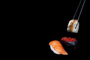 Sushi em uma Preto fundo, Sushi nigiri, caviar e Sushi com enguia ocupado com pauzinhos foto