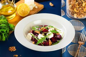 simples, saudável, beterraba ginástica salada. beterraba, feta queijo, Rúcula, nozes, Oliva óleo. azul fundo foto