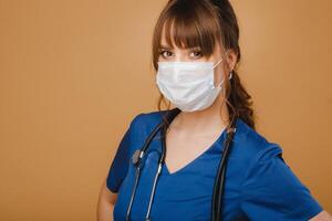 uma menina médico carrinhos dentro uma médico mascarar, isolado em uma Castanho fundo foto