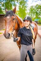 adorável jovem mulher vestindo capacete acariciando para dela Castanho cavalo foto