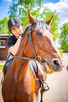 adorável jovem mulher vestindo capacete equitação dela Castanho cavalo foto