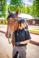 adorável jovem mulher vestindo capacete acariciando para dela Castanho cavalo foto