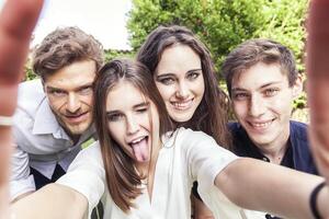 grupo do jovem pessoas levar uma selfie abraçado juntos foto