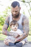 tatuado pai ter Diversão com dele filho dentro a parque foto