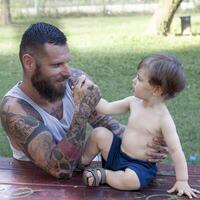 tatuado pai ter Diversão com dele filho dentro a parque foto