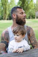 tatuado pai ter Diversão com dele filho dentro a parque foto