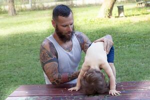 tatuado pai ter Diversão com dele filho dentro a parque foto