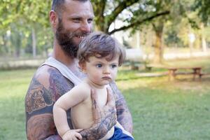 tatuado pai ter Diversão com dele filho dentro a parque foto