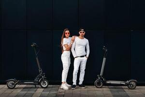 uma menina e uma cara estão caminhando em elétrico patinetes por aí a cidade, uma casal dentro amor em patinetes. foto