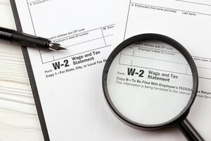 irs Formato w-2 salário e imposto declaração em branco em a4 tábua mentiras em escritório mesa com caneta e ampliação vidro foto