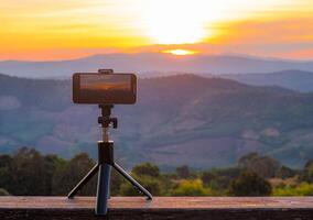 uma Smartphone é gravação a Sol configuração sobre uma montanha faixa. foto