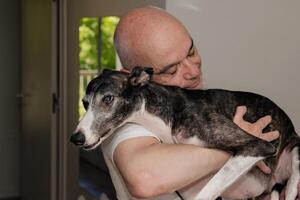 uma Careca meia idade homem com amor segurando dele cachorro. foto
