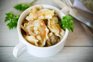 cozinhou dumplings com batatas e frito cebolas em uma de madeira mesa. foto