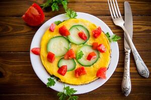 frito omelete com abobrinha, tomates, ervas dentro uma prato foto