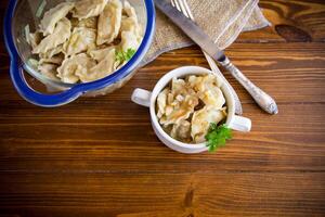 cozinhou dumplings com batatas e frito cebolas em uma de madeira mesa. foto