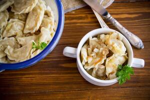 cozinhou dumplings com batatas e frito cebolas em uma de madeira mesa. foto