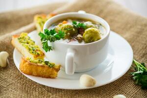 quente cozinhou sopa com Bruxelas brotos, legumes e croutons, dentro uma placa. foto