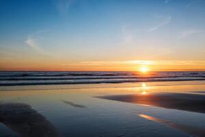 atlântico oceano pôr do sol com surgindo ondas às fonte da telha praia, Portugal foto