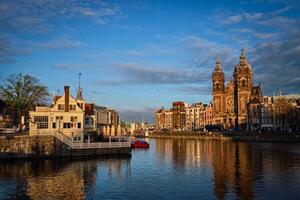 amsterdam canal e Igreja do santo nicholas em pôr do sol foto