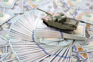 brinquedo tanque em nos cem dólar contas notas. a conceito do guerra custos, militares gastos e econômico crise foto