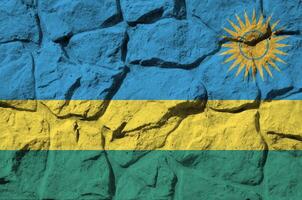 Ruanda bandeira retratado dentro pintura cores em velho pedra parede fechar-se. texturizado bandeira em Rocha parede fundo foto