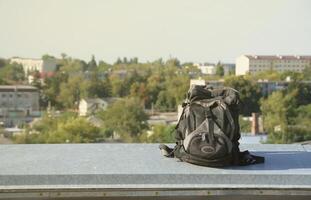 mochila preta fica na borda de metal do telhado do edifício residencial de vários andares em tempo ensolarado foto