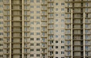 padrão texturizado de uma parede de construção residencial de pedra branca russa com muitas janelas e varanda em construção foto