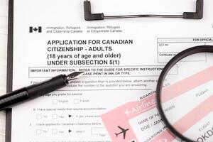 inscrição para canadense cidadania para adultos em a4 tábua mentiras em escritório mesa com caneta e ampliação vidro foto