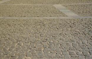 a textura das lajes de pavimentação de muitas pedras pequenas de forma quadrada sob luz solar intensa foto