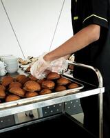 hotel empregados estão preparando lanche bolos em pratos antes a reunião. muitos linhas do pratos com bufê lanches. foto