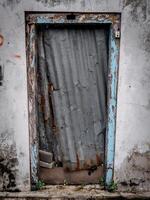 uma estragado porta coberto com zinco Pranchas dentro uma casa este tem fui abandonado de Está proprietário foto