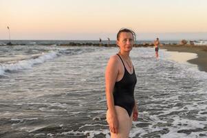 mulher dentro uma Preto roupa de banho outono em a Mediterrâneo mar 2 foto
