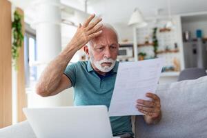 homem preocupado sobre dele por mês pagamentos. sério Senior homem segurando carta sente interessado ler o negócio notícias, obteve convite, aprende banco declaração Informação. postal correspondência conceito foto